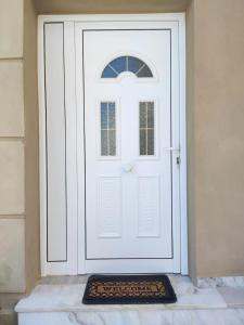 a white door with a welcome mat in front of it at Μοντέρνο Studio στην πόλη Καβάλα(1,5 χμ από ακτή) in Kavala