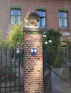 eine Backsteinsäule vor einem Zaun mit einem Blumentopf darauf in der Unterkunft Villa Ritte in Dendermonde