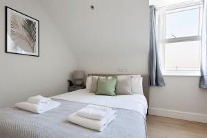 a white bedroom with a bed with two towels on it at The Finchley Apartments in Hendon