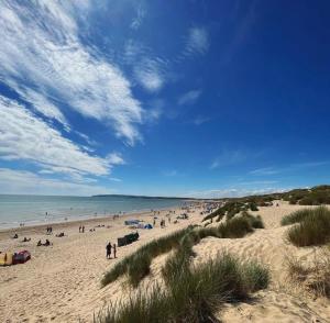 un grupo de personas en una playa cerca del océano en The Beach Huts - Camber Sands, en Camber