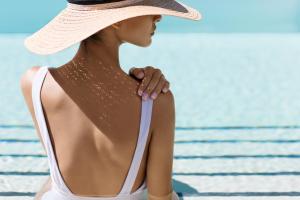 a woman is standing on a beach wearing a hat at Lefay Resort & Spa Lago Di Garda in Gargnano