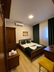 a bedroom with a bed with green curtains and a desk at Hotel Akropoli in Tirana
