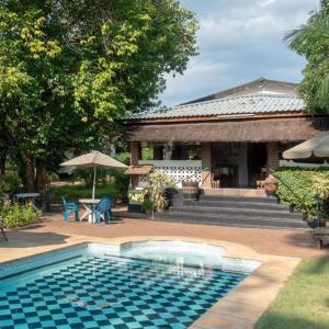 a house with a swimming pool in front of a house at Green Tree Lodge in Livingstone