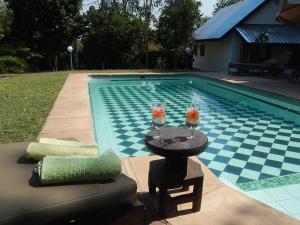 a swimming pool with a table with two glasses on it at Green Tree Lodge in Livingstone