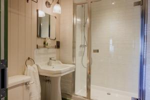 a white bathroom with a sink and a shower at The George & Dragon in Westerham