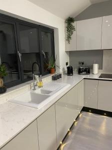 a white kitchen with a sink and a window at Belvedare-Suffolk in Sudbury