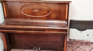 an old piano is sitting in a room at REST HOUSE Casa familiar - garage - TV - WiFi - 2 dormitorios - Living-comedor - Cocina - Lavadero - Patio con parrilla - Alquiler temporario in Concepción del Uruguay