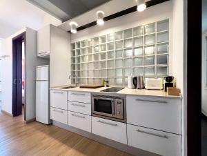 a kitchen with white cabinets and a microwave at Stay U-nique Apartments Colom in Barcelona