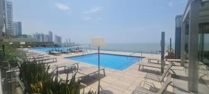a swimming pool with chairs and the ocean in the background at H2 Hyatt Vista Mar!! in Cartagena de Indias