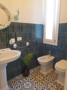 uma casa de banho com um lavatório, um WC e um espelho. em Dimora Quattro Vanelle em Favignana