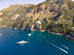 a boat in the water next to a mountain at Grand Hotel Tritone in Praiano