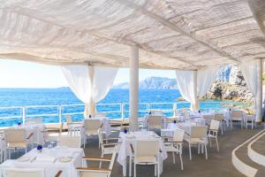 a restaurant with white tables and chairs and the ocean at Grand Hotel Tritone in Praiano