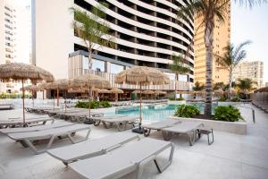 a pool with tables and umbrellas and a building at Hotel Primavera Park in Benidorm