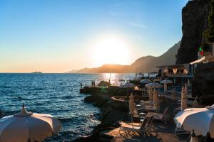 a beach with umbrellas and chairs and the ocean at Grand Hotel Tritone in Praiano