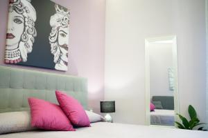 una camera da letto con letto, cuscini rosa e specchio di Tyche apartaments & rooms a Taormina