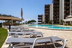 a row of chaise lounge chairs next to a swimming pool at Atrium Studio Cascais in Cascais