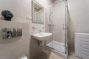 La salle de bains blanche est pourvue d'un lavabo et d'une douche. dans l'établissement InshiApartments on Pid Dubom str, à Lviv