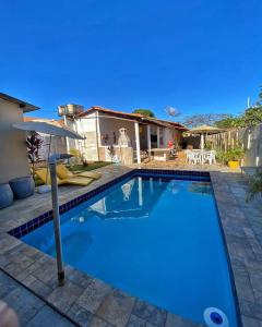 a swimming pool with an umbrella and a house at CASA ALUNAI in Pirenópolis