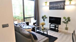 a living room with a couch and a tv at MK shortstay Deluxe- Capital Drive in Milton Keynes