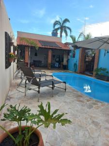 un patio avec deux chaises à côté d'une piscine dans l'établissement Pousada Flores em Vida, à Olímpia