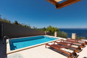 a swimming pool with chaise lounge chairs and the ocean at Seafront Stone Villa in Blato