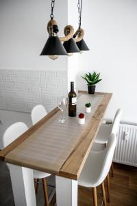 comedor con mesa de madera y sillas blancas en Apartman Minja, en Subotica