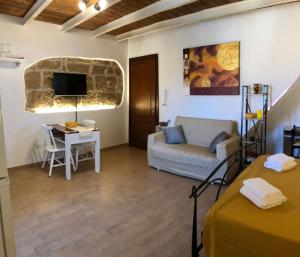 ein Wohnzimmer mit Sofa und Schreibtisch mit Fernseher in der Unterkunft Ninfa Alghero in Alghero