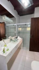 a bathroom with a sink and a glass shower at Pousada Cozy House in Itaipava