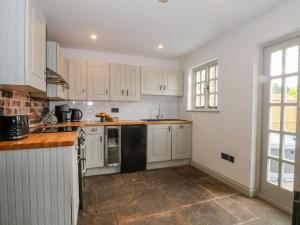 a kitchen with white cabinets and a black refrigerator at The Coach House in Crewe