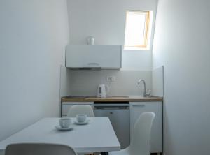 a small white kitchen with a table and chairs at Villa Sandra Lagadin in Ohrid