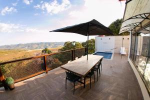 balcón con mesa de madera y sombrilla en Horizonte de Lavras, en Lavras Novas