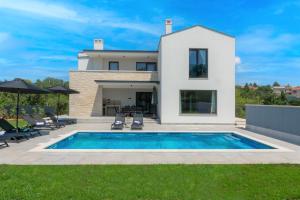 a villa with a swimming pool in front of a house at Modern 300m2 Villa - King Beds & Leisure Zone in Tinjan