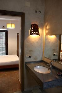 a bathroom with a sink and a mirror and a bed at Hostal Extramuros in Conil de la Frontera