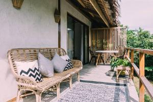 Un banco de mimbre sentado en un porche con almohadas. en Eden, en El Nido