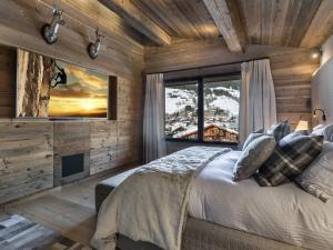 una camera da letto con un letto e una grande finestra di Chalet de luxe avec jacuzzi, salle cinéma et piscine au centre de Megève - FR-1-569-10 a Megève