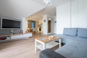 salon z kanapą i telewizorem w obiekcie Apartament Holiday w Darłówku