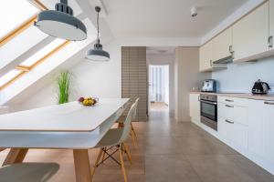 kuchnia z białymi szafkami, stołem i krzesłami w obiekcie Apartament Holiday w Darłówku