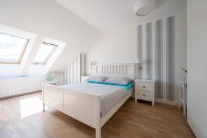 biała sypialnia z białym łóżkiem i 2 oknami w obiekcie Apartament Holiday w Darłówku
