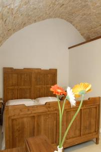 1 dormitorio con cama de madera y jarrón con flores en B&B Parco del Lamione, en Gioia del Colle