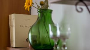 a green glass vase with flowers in it next to a book at B&B Casa Baronale in Castelsaraceno