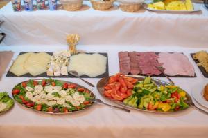 a table with plates of food and meats and vegetables at Mikulov Inn - Apartments Slunce in Mikulov