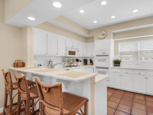 a kitchen with white cabinets and a counter with chairs at Hidden Dunes Villa 44 in Destin