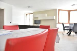 ein Esszimmer mit roten Stühlen und einem Tisch in der Unterkunft La Pieve Apartments in San Lorenzo in Banale