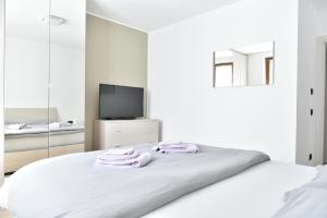 ein weißes Schlafzimmer mit einem Bett mit Handtüchern darauf in der Unterkunft La Pieve Apartments in San Lorenzo in Banale