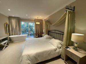 a bedroom with a bed and a tub and a sink at Casa da Quineira Boutique Hotel in Chapada dos Guimarães