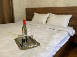 卡兹贝吉Story Guesthouse的床上的托盘,包括一瓶葡萄酒和两杯酒