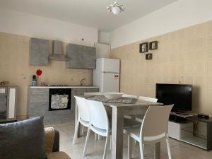 a kitchen with a table and white chairs in a kitchen at il sole nei templi in Castelvetrano Selinunte