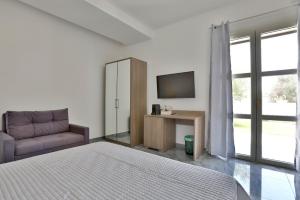 a bedroom with a bed and a tv and a couch at Villa Alfi in Galatina