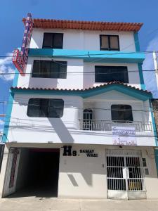 ein weißes Gebäude mit einem Schild davor in der Unterkunft HOSPEDAJE SAMAY WASI (AYACUCHO) in Ayacucho