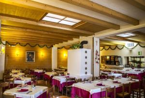 uma sala de jantar com mesas e cadeiras com toalha de mesa roxa em Hotel Al Pelmo Wellness em Pieve di Cadore